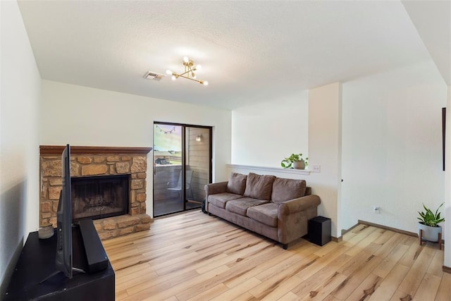 14405 N Pennsylvania Ave Unit 6D, Oklahoma City, OK 73134 - living room with light wood-style flooring, a stone fireplace, and a textured ceiling