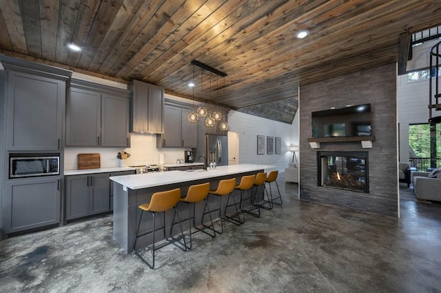 316 Triton Trl, Broken Bow, OK 74728 - kitchen with appliances with stainless steel finishes, concrete floors, gray cabinetry, wood ceiling, and a kitchen bar