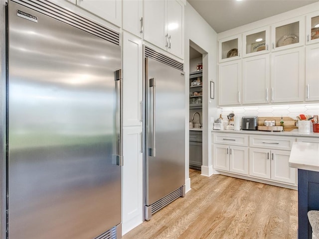 22795 Cterling Dr, Kingfisher, OK 73750 - kitchen featuring built in fridge, light wood finished floors, light countertops, and white cabinets