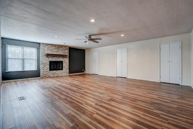 3208 NW 47th St, Oklahoma City, OK 73112 - unfurnished living room featuring ceiling fan, wood finished floors, a textured ceiling, recessed lighting, and a stone fireplace