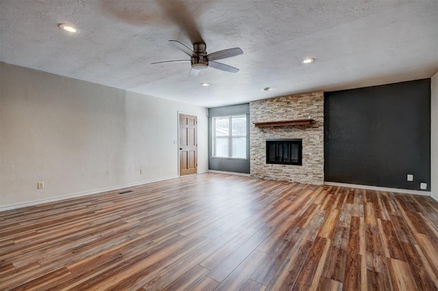 3208 NW 47th St, Oklahoma City, OK 73112 - unfurnished living room with wood finished floors, a ceiling fan, a fireplace, recessed lighting, and a textured ceiling