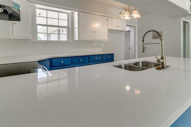 5309 S Blackwelder Ave, Oklahoma City, OK 73119 - kitchen with extractor fan, blue cabinets, light countertops, white cabinetry, and decorative backsplash