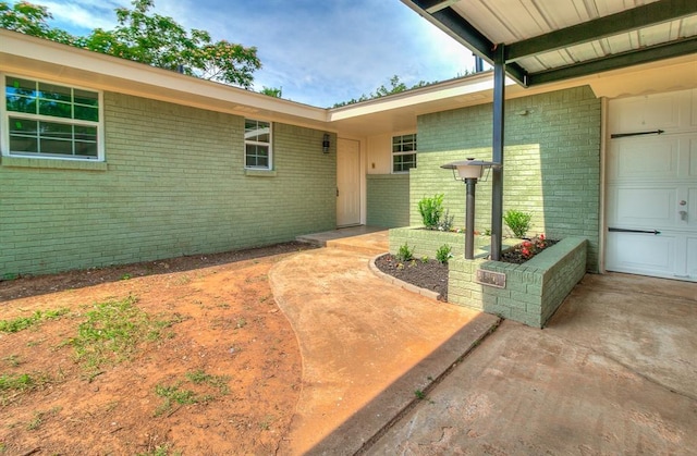 5309 S Blackwelder Ave, Oklahoma City, OK 73119 - doorway to property featuring brick siding, an attached garage, and driveway