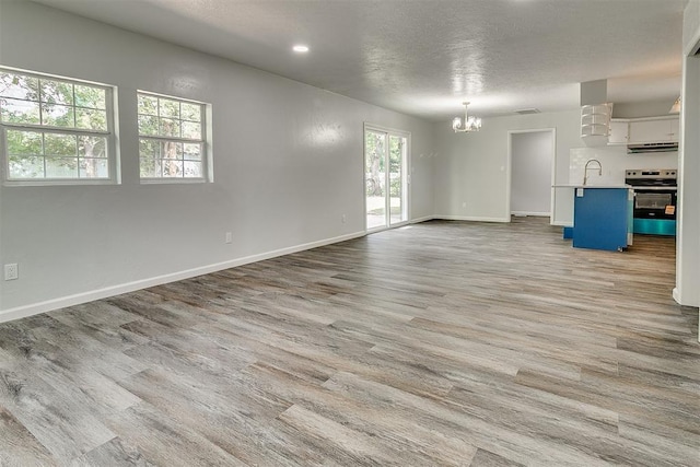 5309 S Blackwelder Ave, Oklahoma City, OK 73119 - unfurnished living room with a chandelier, wood finished floors, recessed lighting, and a textured ceiling