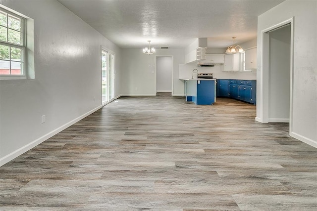 5309 S Blackwelder Ave, Oklahoma City, OK 73119 - kitchen featuring blue cabinetry, a chandelier, wall chimney exhaust hood, and healthy amount of natural light