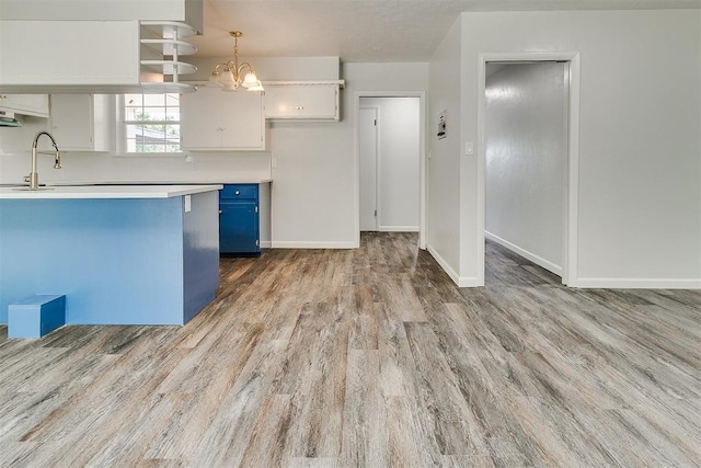 5309 S Blackwelder Ave, Oklahoma City, OK 73119 - kitchen with blue cabinetry, wood finished floors, light countertops, a chandelier, and white cabinetry