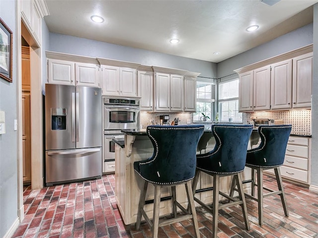 4304 Riders Mark, Edmond, OK 73025 - kitchen with appliances with stainless steel finishes, brick floors, a kitchen bar, tasteful backsplash, and recessed lighting
