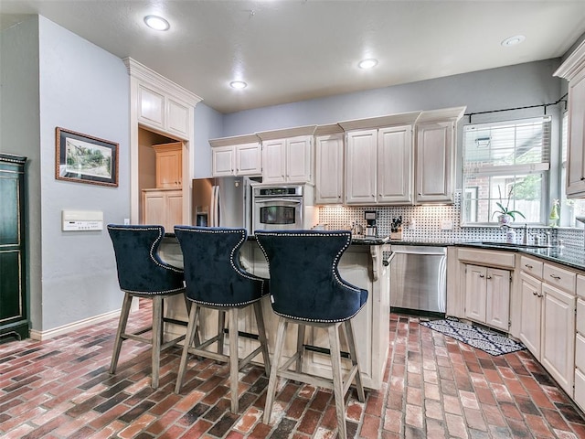 4304 Riders Mark, Edmond, OK 73025 - kitchen with stainless steel appliances, a breakfast bar area, brick floors, decorative backsplash, and recessed lighting