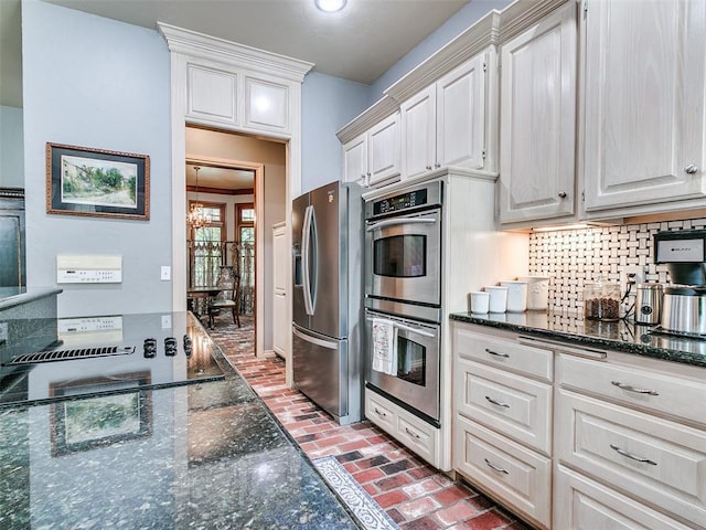 4304 Riders Mark, Edmond, OK 73025 - kitchen featuring stainless steel appliances, a chandelier, brick floors, backsplash, and dark stone countertops