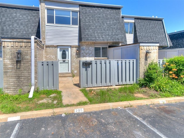 205 Jason Dr, Norman, OK 73071 - rear view of property featuring brick siding, a shingled roof, and uncovered parking
