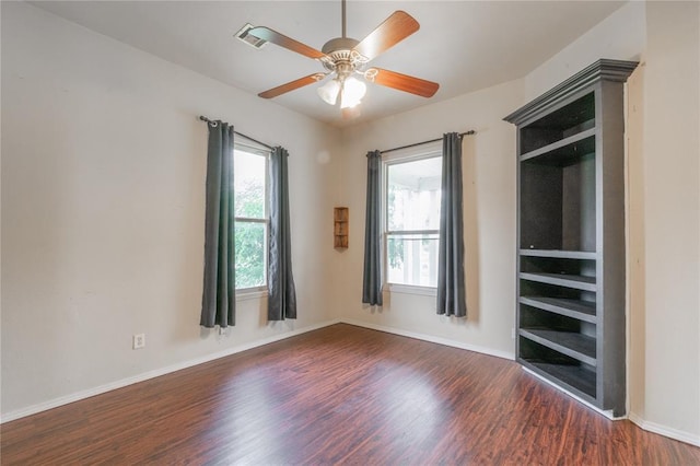 502 S 7th St, Chickasha, OK 73018 - unfurnished bedroom with multiple windows, dark wood finished floors, and a ceiling fan