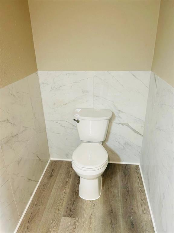 202 W Oak Ave, Seminole, OK 74868 - bathroom featuring wainscoting, wood finished floors, and tile walls