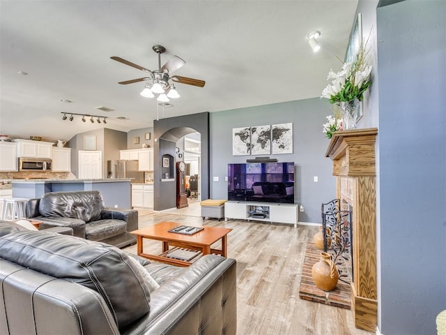 517 Firefork Ave, Yukon, OK 73099 - living area with ceiling fan, arched walkways, light wood-type flooring, a brick fireplace, and rail lighting