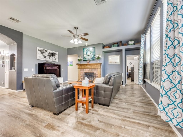 517 Firefork Ave, Yukon, OK 73099 - living room featuring light wood finished floors, arched walkways, a brick fireplace, and ceiling fan