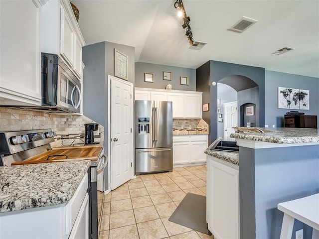 517 Firefork Ave, Yukon, OK 73099 - kitchen with appliances with stainless steel finishes, arched walkways, tasteful backsplash, white cabinetry, and light tile patterned floors