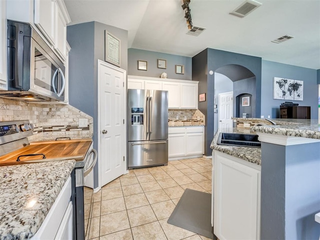 517 Firefork Ave, Yukon, OK 73099 - kitchen featuring appliances with stainless steel finishes, arched walkways, backsplash, white cabinets, and light tile patterned flooring