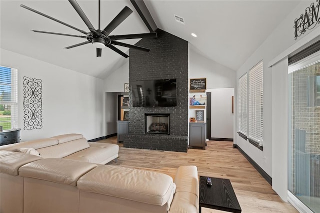 1031 Colonial Ave, Tuttle, OK 73089 - living area featuring light wood finished floors, a fireplace, beam ceiling, ceiling fan, and high vaulted ceiling