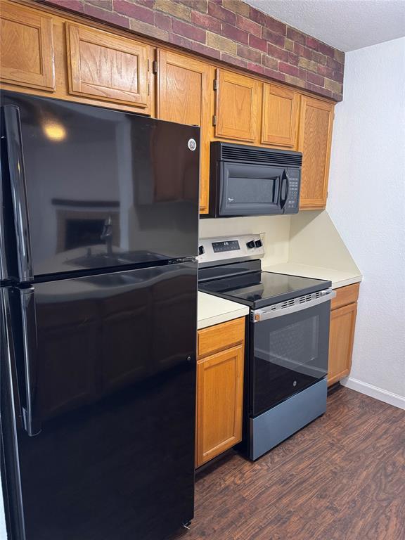 3000 Chautauqua Ave Unit 208, Norman, OK 73072 - kitchen featuring black appliances, dark wood-type flooring, light countertops, and a textured ceiling