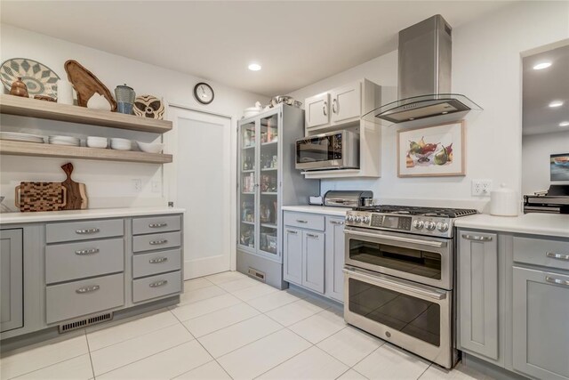 15700 N Western Ave, Edmond, OK 73013 - kitchen with stainless steel appliances, island range hood, gray cabinetry, light countertops, and light tile patterned flooring