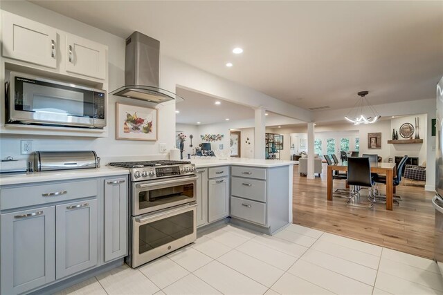 15700 N Western Ave, Edmond, OK 73013 - kitchen featuring stainless steel appliances, island range hood, a peninsula, gray cabinets, and light countertops