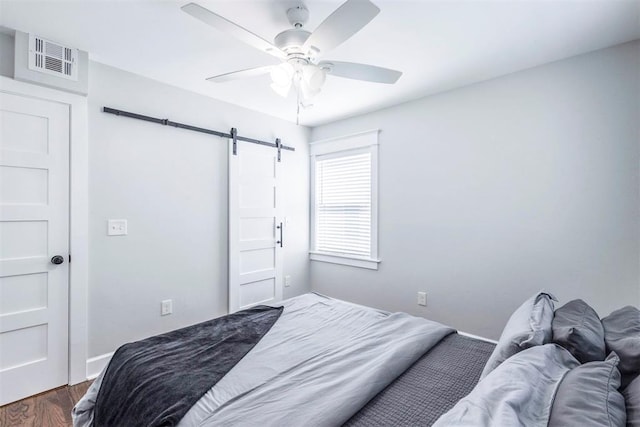 1218 N Brookline Ave, Oklahoma City, OK 73107 - bedroom featuring a barn door, dark wood-style floors, and ceiling fan