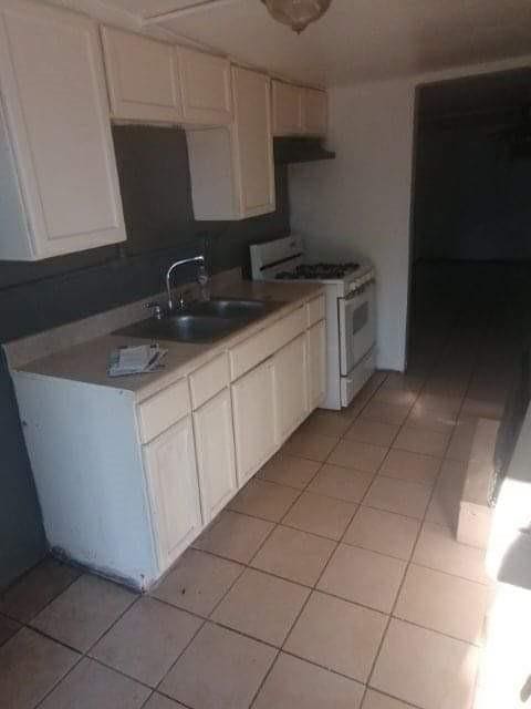 2904 S Indiana Ave, Oklahoma City, OK 73108 - kitchen featuring white gas range, light tile patterned floors, and white cabinetry