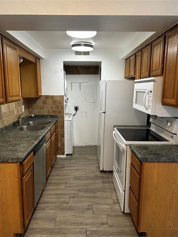 11130 Stratford Dr Unit 418, Oklahoma City, OK 73120 - kitchen featuring white appliances, washer / clothes dryer, dark countertops, wood finished floors, and brown cabinets