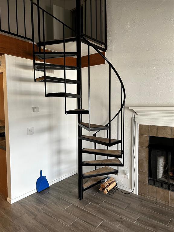 11130 Stratford Dr Unit 418, Oklahoma City, OK 73120 - staircase featuring wood finished floors, a tile fireplace, and a textured wall