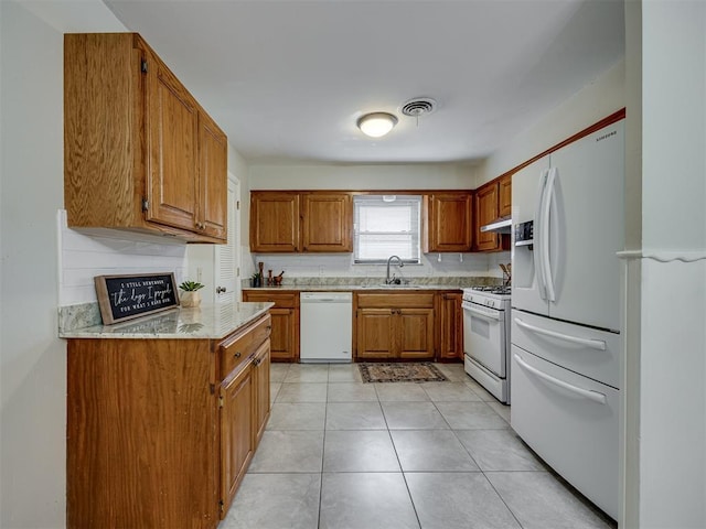 5936 N Ione Dr, Oklahoma City, OK 73122 - kitchen featuring white appliances, brown cabinets, light tile patterned flooring, light stone countertops, and under cabinet range hood