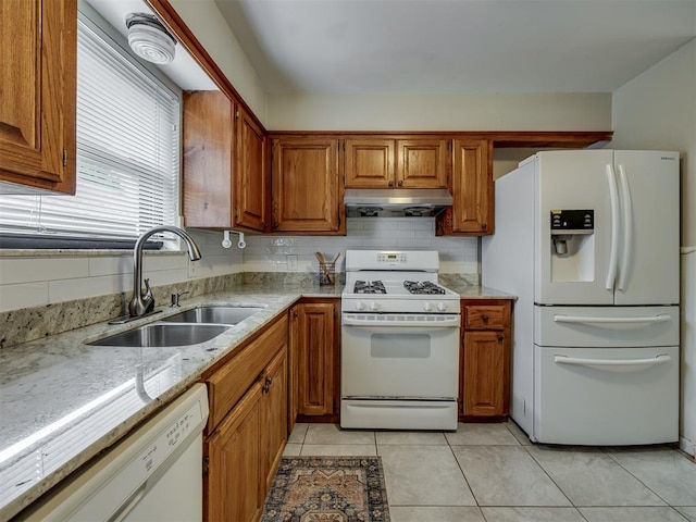 5936 N Ione Dr, Oklahoma City, OK 73122 - kitchen with white appliances, under cabinet range hood, brown cabinets, light tile patterned floors, and light stone counters