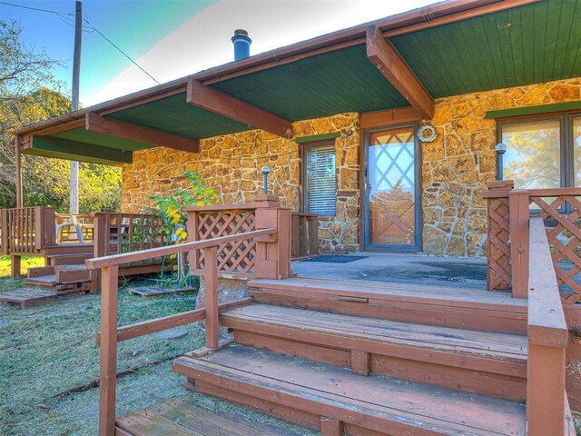 5905 NW 50th St, Oklahoma City, OK 73122 - doorway to property featuring stone siding and a wooden deck