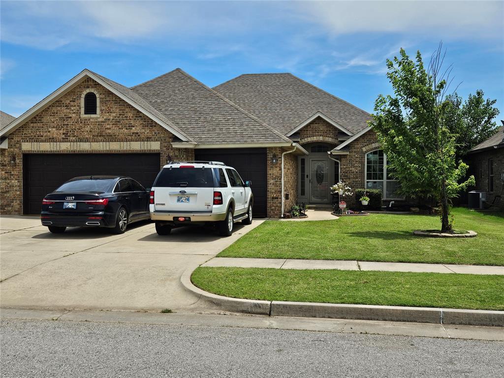 3212 San Juan Trl, Moore, OK 73160 - view of front of house featuring a garage, brick siding, concrete driveway, a front yard, and roof with shingles