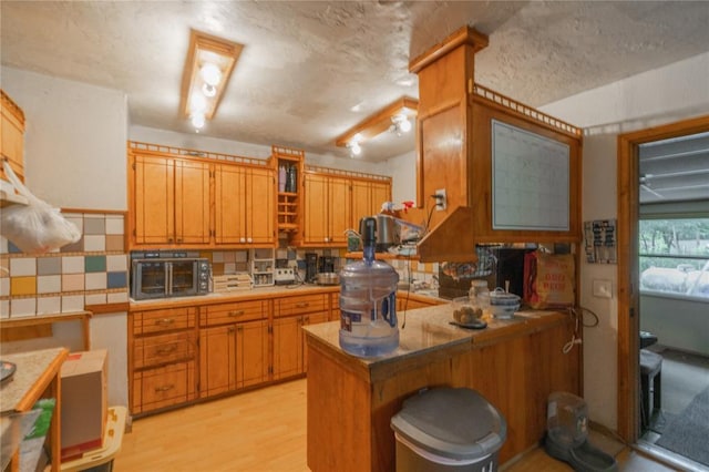 17856 Beechnut Ln, Alex, OK 73003 - kitchen featuring a peninsula, decorative backsplash, light wood finished floors, a textured ceiling, and brown cabinets