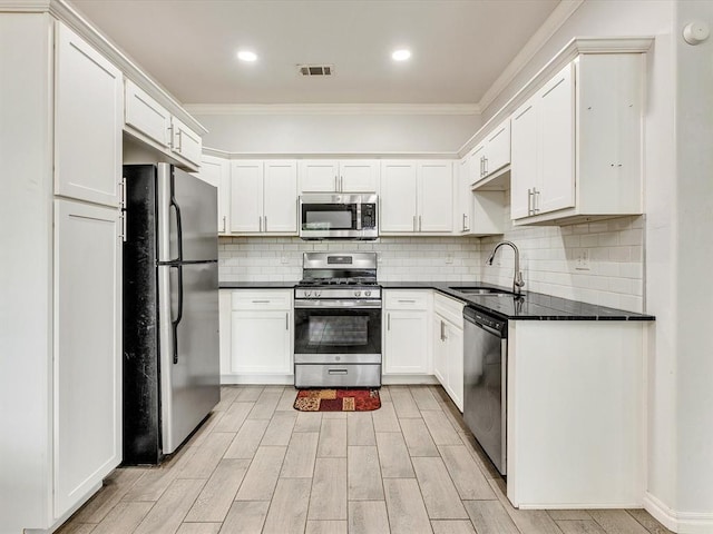 837 SE 68th St, Oklahoma City, OK 73149 - kitchen featuring appliances with stainless steel finishes, ornamental molding, dark countertops, light wood-type flooring, and decorative backsplash