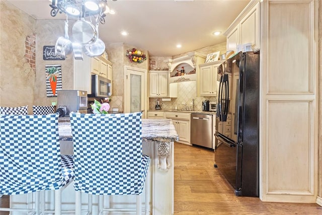 1414 Chisholm Trl, Weatherford, OK 73096 - kitchen featuring stainless steel appliances, cream cabinetry, a peninsula, light wood-type flooring, and recessed lighting