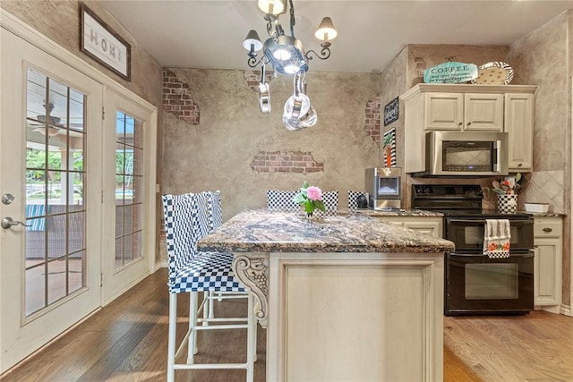 1414 Chisholm Trl, Weatherford, OK 73096 - kitchen with stainless steel microwave, black range with electric cooktop, stone countertops, and wood finished floors