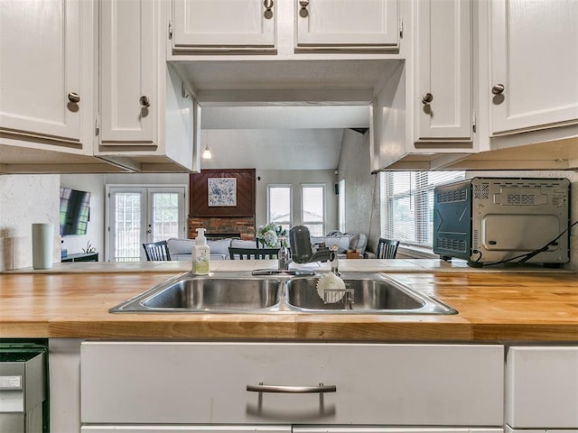 401 NW 120th St, Oklahoma City, OK 73114 - kitchen with butcher block counters, white cabinets, a fireplace, and plenty of natural light