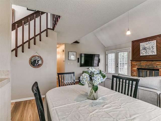 401 NW 120th St, Oklahoma City, OK 73114 - dining space featuring wood finished floors, a textured ceiling, a fireplace, lofted ceiling, and stairs