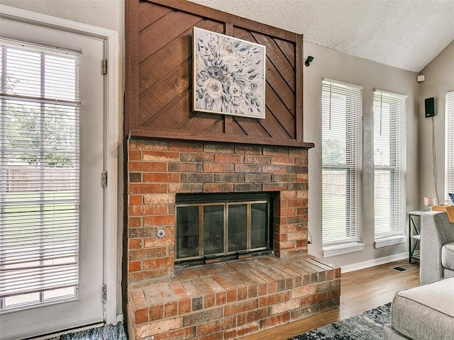 401 NW 120th St, Oklahoma City, OK 73114 - living area featuring a fireplace, lofted ceiling, wood finished floors, and a textured ceiling