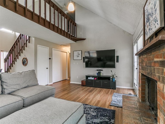 401 NW 120th St, Oklahoma City, OK 73114 - living area featuring high vaulted ceiling, a fireplace, wood finished floors, a textured ceiling, and stairway