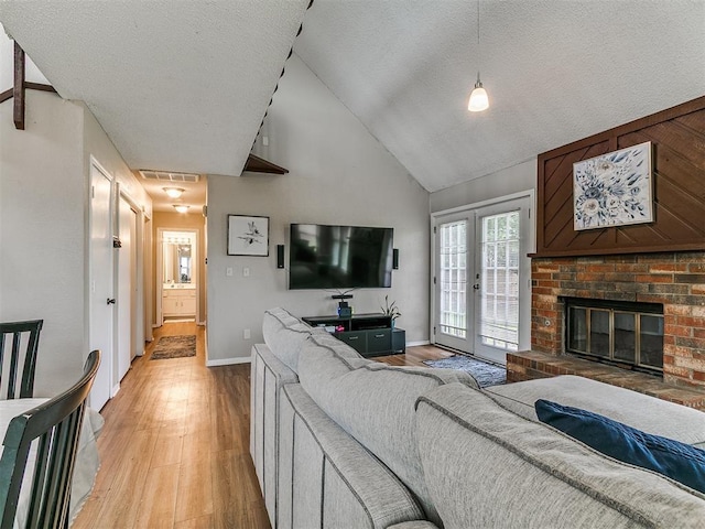 401 NW 120th St, Oklahoma City, OK 73114 - living area with light wood-type flooring, high vaulted ceiling, a fireplace, french doors, and a textured ceiling