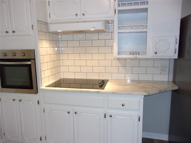 3018 N Beard Ave, Shawnee, OK 74804 - kitchen with oven, exhaust hood, black electric stovetop, white cabinetry, and backsplash