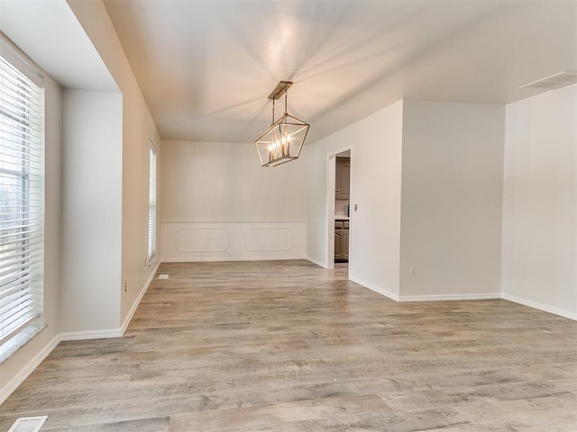 2317 NW 119th St, Oklahoma City, OK 73120 - empty room featuring healthy amount of natural light, a chandelier, and light wood finished floors