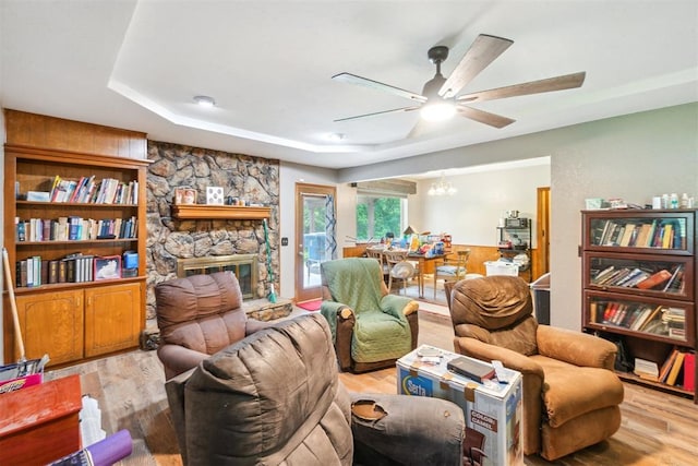 3414 Clayton Dr, Tuttle, OK 73089 - living area with ceiling fan, wood finished floors, a raised ceiling, a chandelier, and a stone fireplace