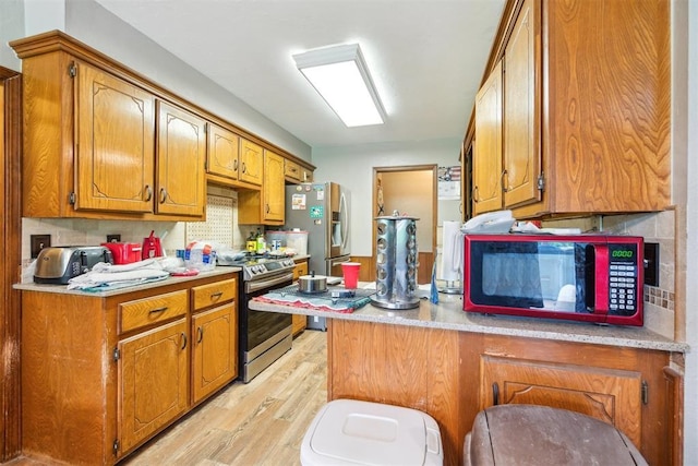 3414 Clayton Dr, Tuttle, OK 73089 - kitchen featuring stainless steel appliances, light wood-style flooring, brown cabinetry, and a peninsula
