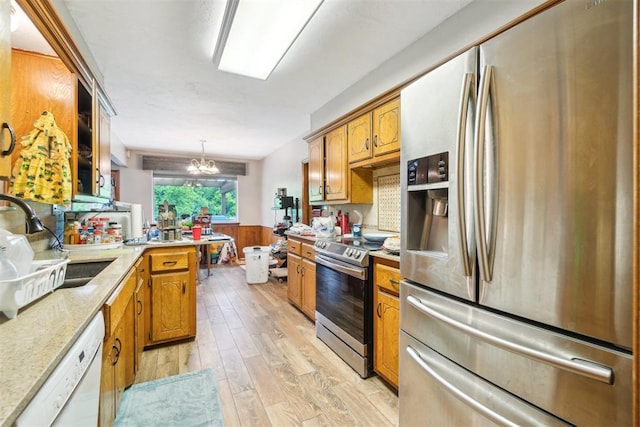 3414 Clayton Dr, Tuttle, OK 73089 - kitchen with stainless steel appliances, light wood-type flooring, wainscoting, a chandelier, and brown cabinets
