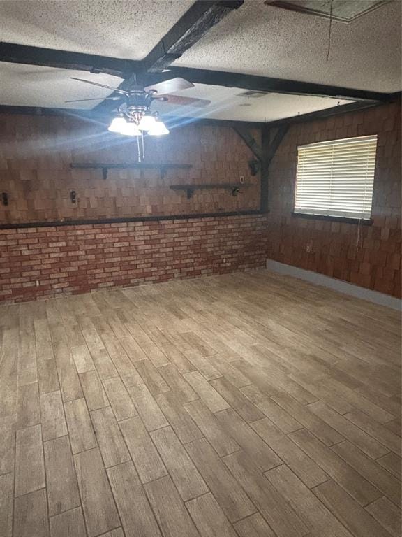 5517 S Karen St, Oklahoma City, OK 73135 - empty room featuring a textured ceiling, brick wall, a ceiling fan, wooden walls, and wood finished floors