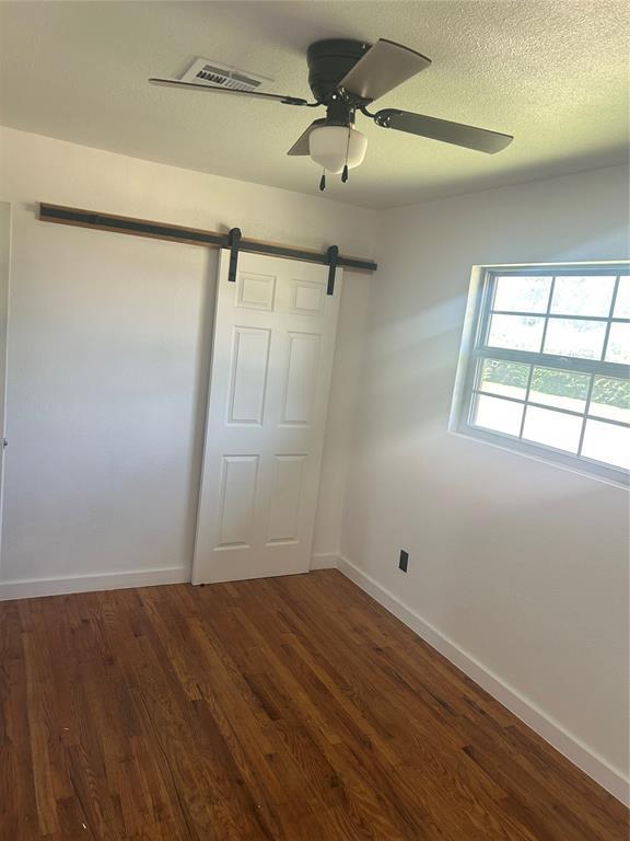 5326 NW Columbia Ave, Lawton, OK 73505 - empty room with a barn door, wood finished floors, and a ceiling fan