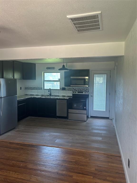 5326 NW Columbia Ave, Lawton, OK 73505 - kitchen with stainless steel appliances, dark wood-type flooring, a textured wall, a textured ceiling, and pendant lighting