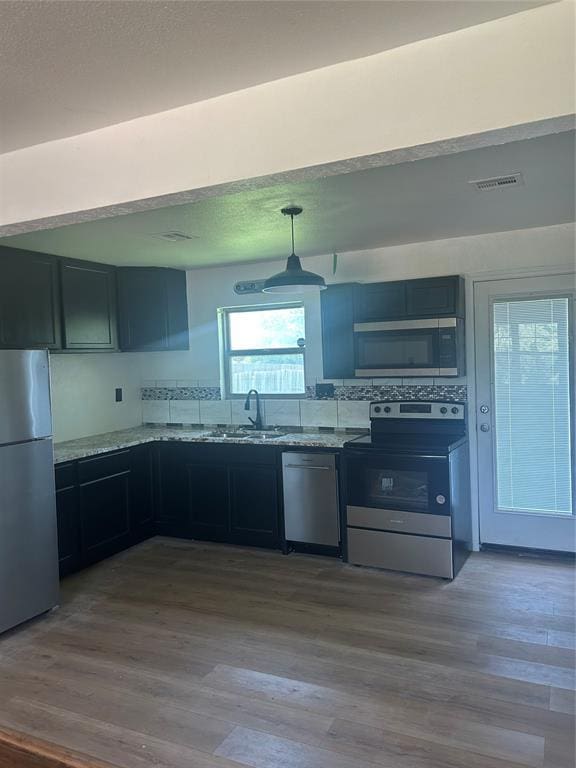 5326 NW Columbia Ave, Lawton, OK 73505 - kitchen featuring appliances with stainless steel finishes, wood finished floors, light stone countertops, and hanging light fixtures